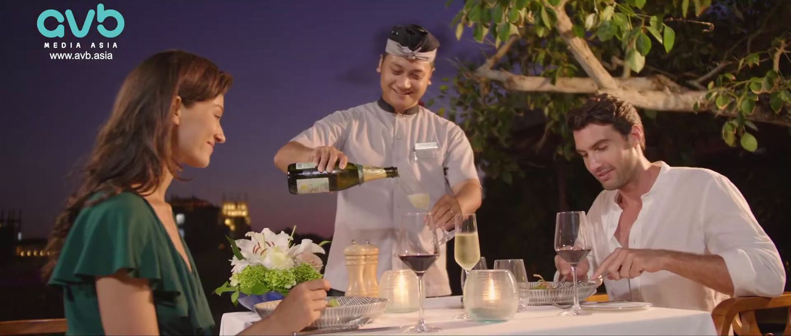 a man pouring a glass of wine to a woman at a table