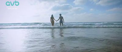 two people holding hands walking into the ocean