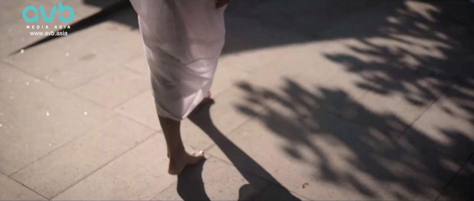 a woman walking down a sidewalk in a white dress