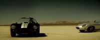 a silver car and a silver sports car in a desert