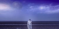 a man in a white robe standing on a beach