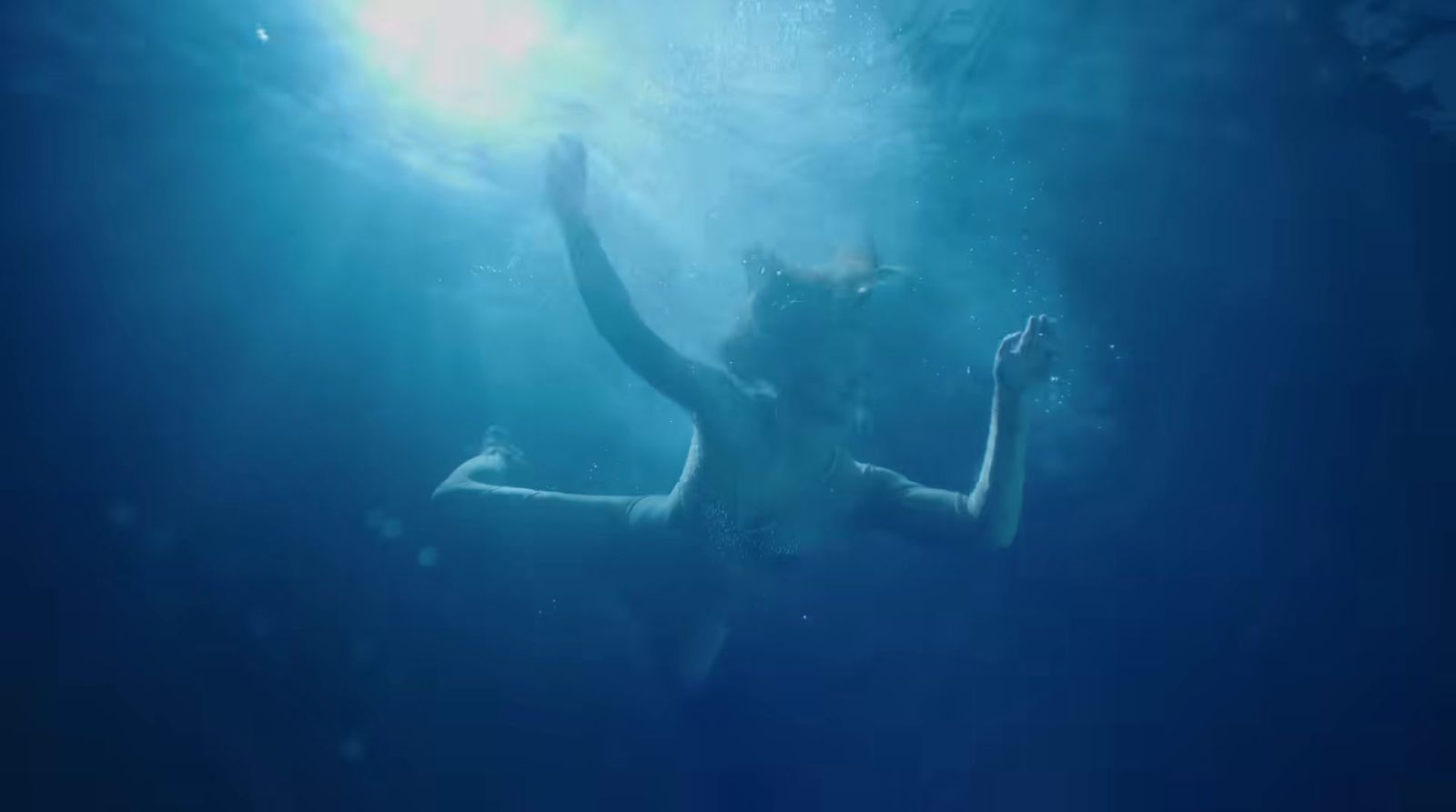 a woman in a body of water with her arms in the air