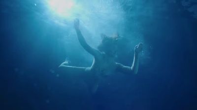 a woman in a body of water with her arms in the air