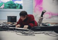 a young man sitting on the floor working on a laptop