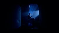 a person sitting on a stool in a dark room