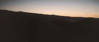 a black and white photo of a mountain at sunset