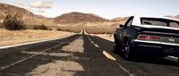 a black sports car driving down a desert road