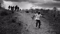 a black and white photo of a group of people running up a hill