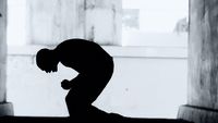 a silhouette of a man kneeling in front of a doorway