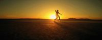 a person standing in the middle of a field at sunset