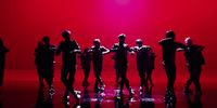 a group of people standing in front of a red background