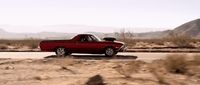 a red car driving down a desert road