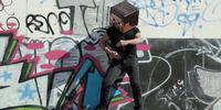 a man standing on a skateboard in front of a wall covered in graffiti