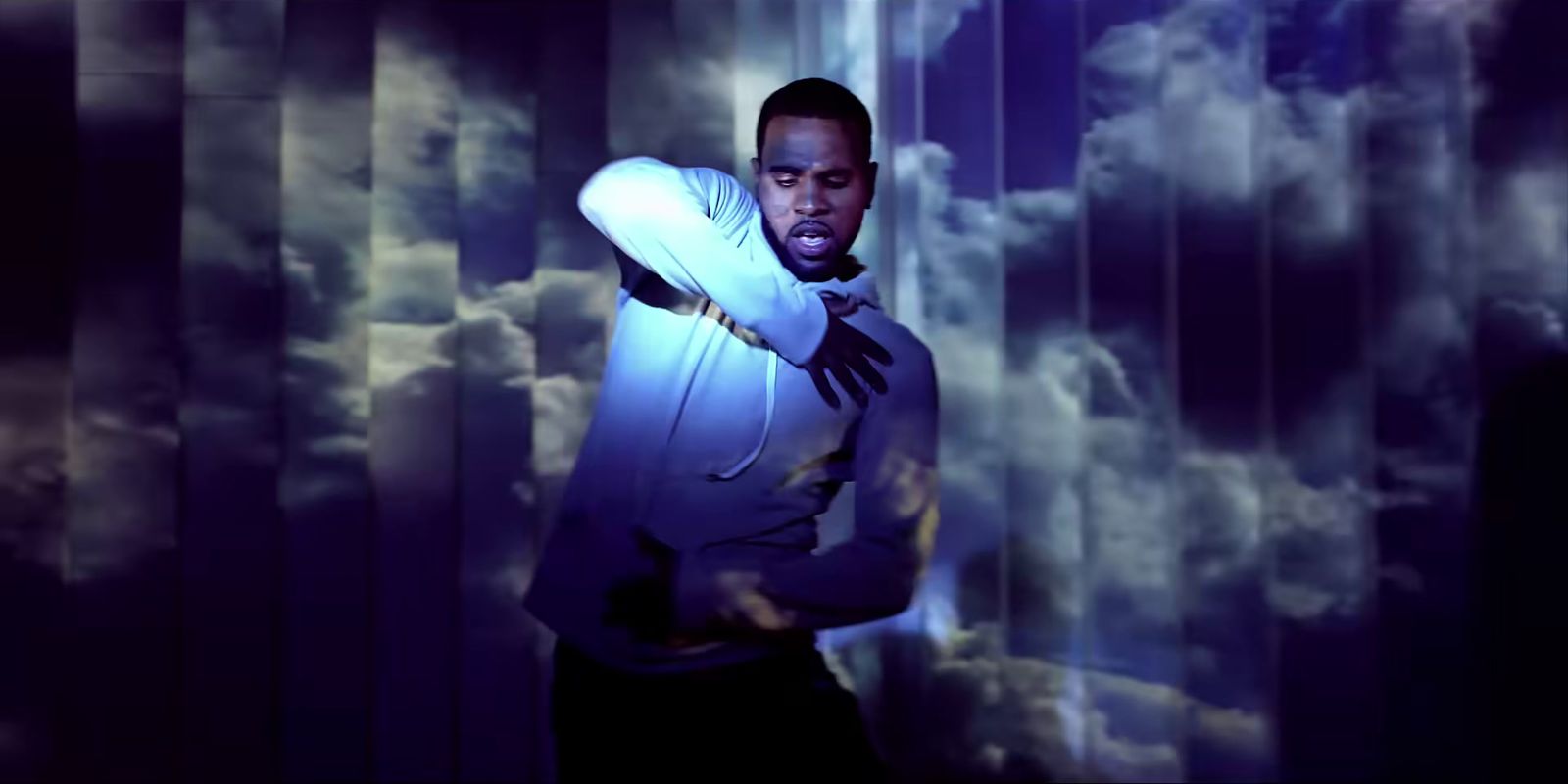 a man standing in front of a curtain with clouds in the background