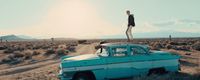 a man standing on top of a car in the middle of a desert