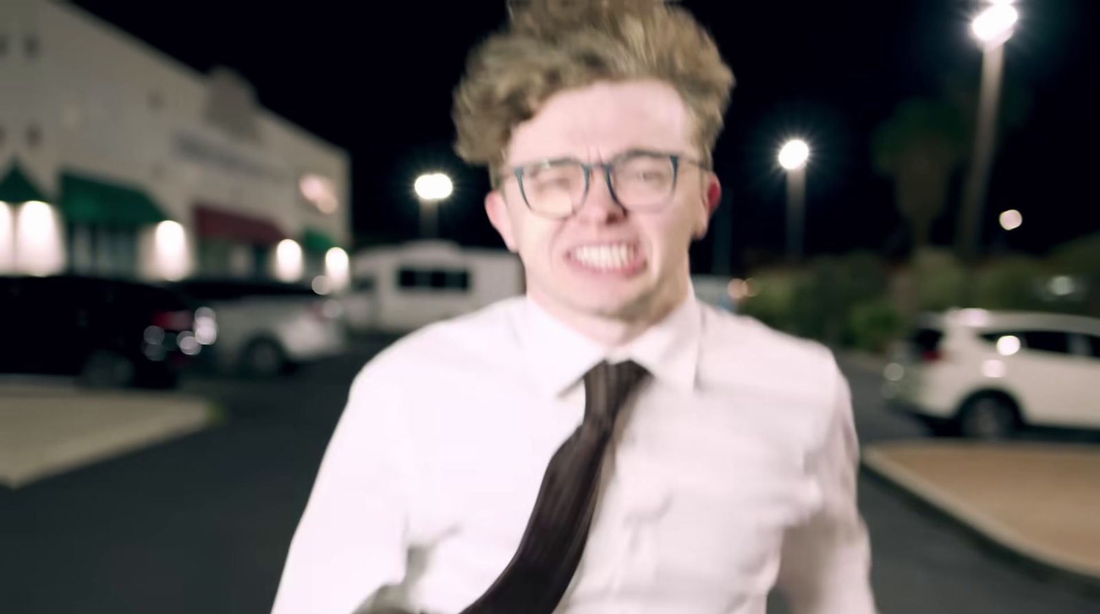 a man wearing glasses and a tie standing on a street