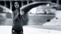 a woman standing in front of a bridge holding her hands together