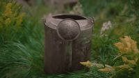 a metal trash can sitting in the middle of a field