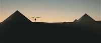 a person standing on top of a hill next to three pyramids