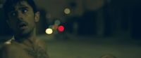 a shirtless man standing in the middle of a street at night