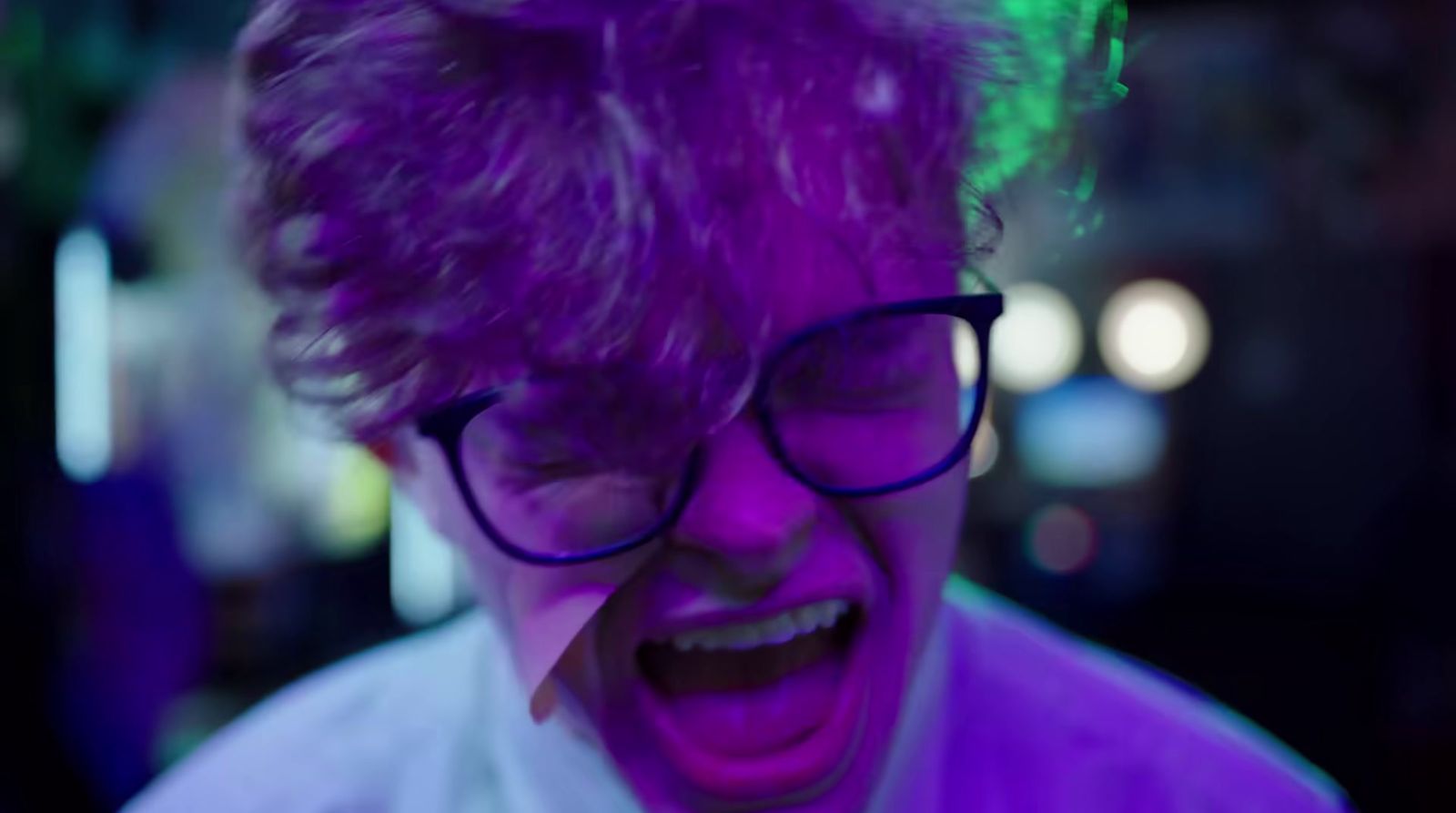 a man with purple hair and glasses laughing