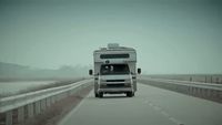 a white truck driving down a road next to a large truck