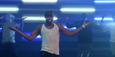 a man in a white tank top standing in front of a group of people