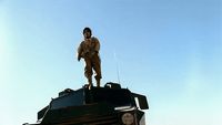 a soldier standing on top of a tank