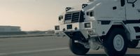 a large white armored vehicle driving down a road