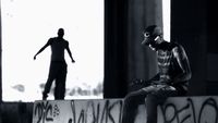 a man sitting on a wall next to a skateboard