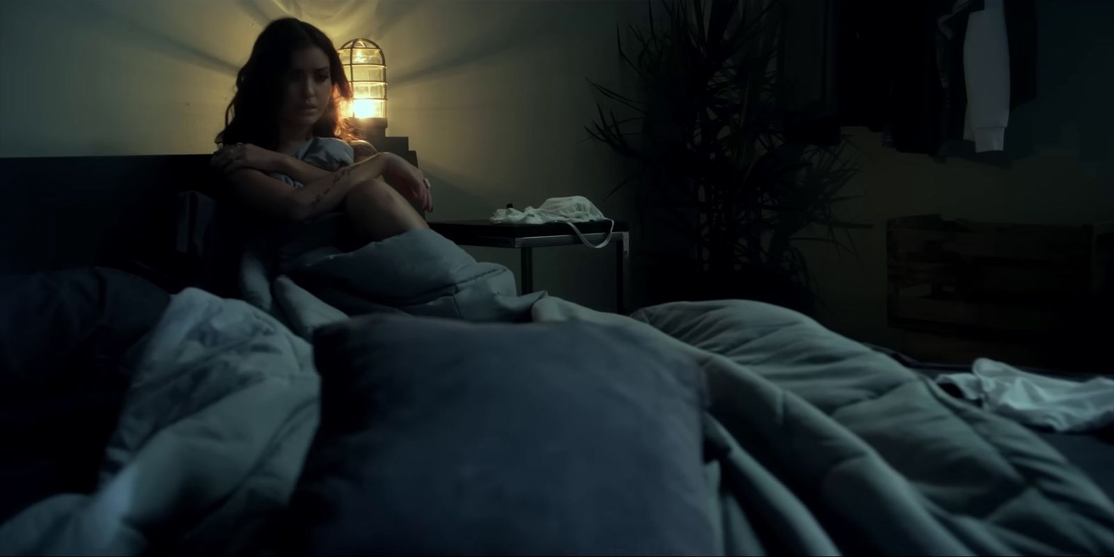 a woman sitting on a bed in a dark room