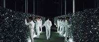 a group of men walking down a tunnel of hedges