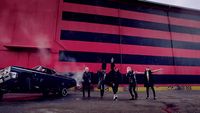 a group of men standing next to a black car