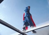 a man in a blue and red jacket is doing a trick on a skateboard