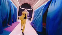 a man in a yellow suit walking down a runway