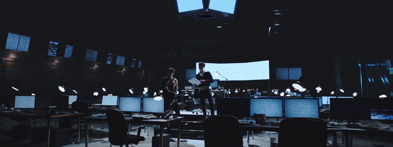 a group of people in a dark room with lots of monitors