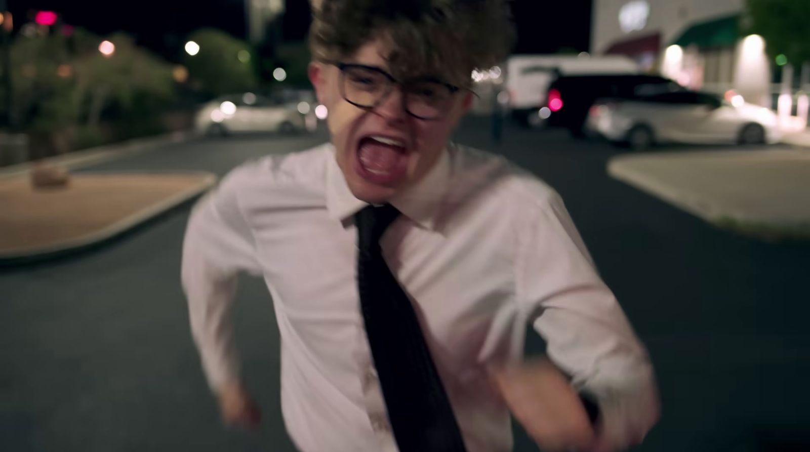 a man with glasses and a tie making a face