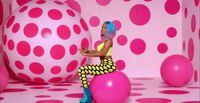 a woman sitting on top of a pink ball