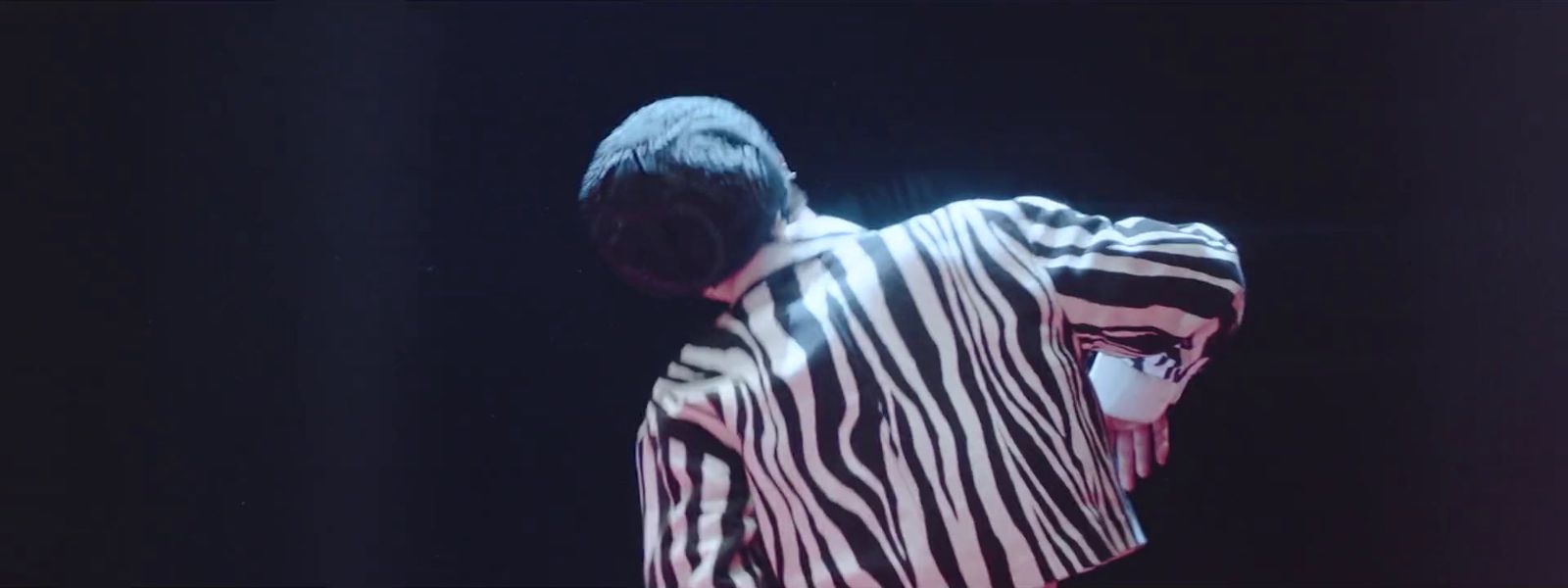 a man in a zebra print shirt standing in front of a black background