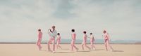 a group of men in pink suits walking across a desert