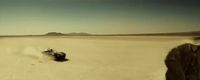 a car driving through a desert with a mountain in the background