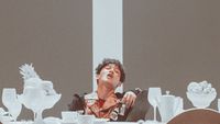 a man sitting at a table with plates and cups