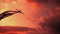 a plane flying through a cloudy sky with a sunset in the background