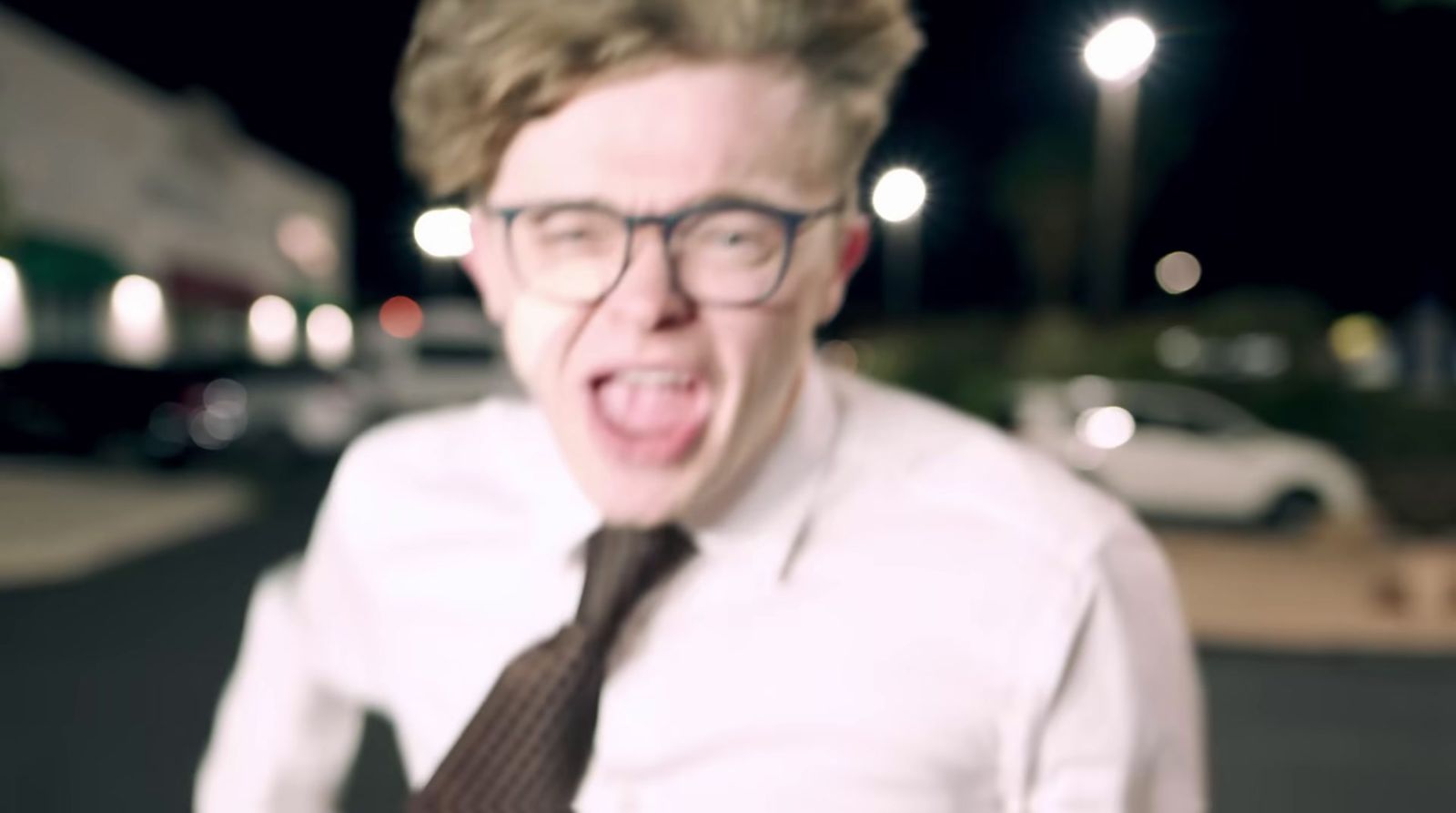 a man with glasses and a tie making a silly face