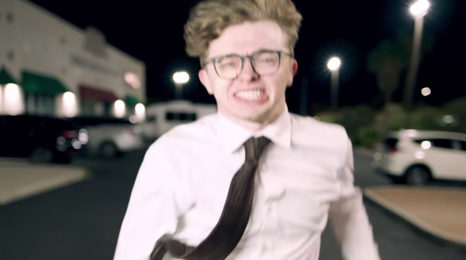 a man wearing glasses and a tie standing on a street