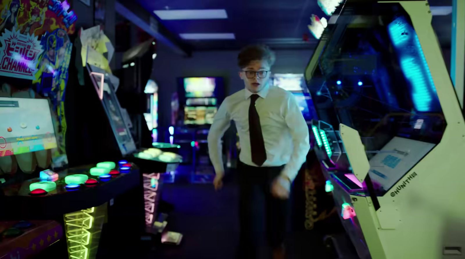 a man in a tie is standing in a room with pinball machines