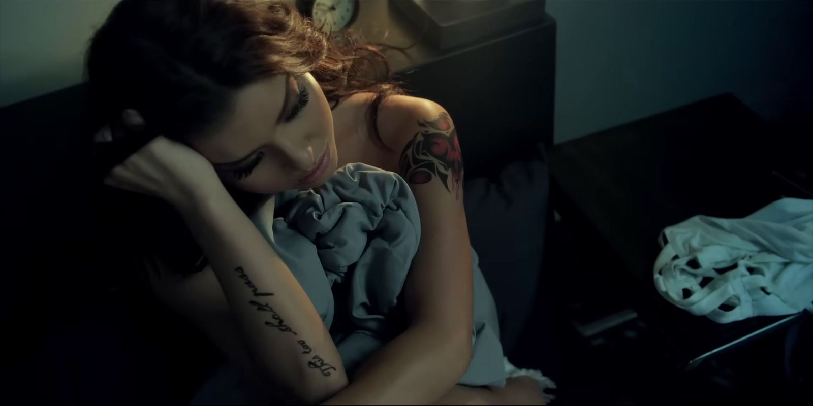 a woman sitting on a couch with a tattoo on her arm