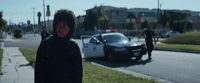 a man in a hoodie standing next to a police car