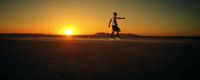 a man riding a skateboard across a field at sunset