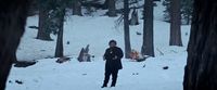 a man standing in the snow next to a forest